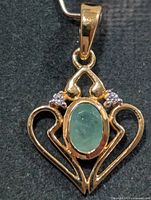 Front view of pendant showing emerald, clear stones and heart design