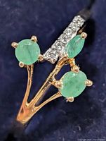 Top view of ring showing three emeralds and accent stones