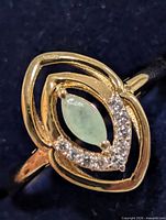 Frontal close-up of ring detailing emerald and accent stones