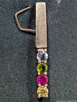 Front view of silver pendant showing four gemstones and bail