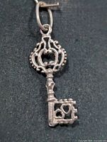 Front view of ornate silver key pendant