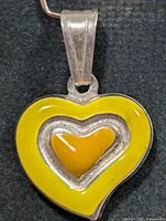 Front view of silver heart pendant with yellow enamel detail
