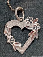 Front view of silver heart pendant showing floral accents and jump ring
