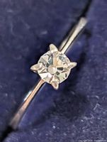 close-up of the ring showing round clear stone in six-prong setting on silver-tone band