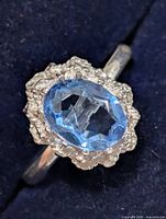 Close view of ring top showing blue oval gemstone and textured surround