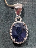 front view of sterling silver pendant with blue sapphire center and halo accents