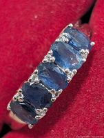 Front view of ring showing five oval sapphires and accent stones