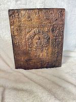 full view of rectangular brass plaque front showing central Buddha and surrounding panels