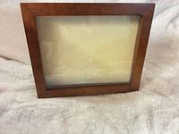 Front view of brown wood shadow box frame with glass front