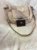 Beige pebbled leather Coach shoulder bag with adjustable strap and burgundy patent wallet in front