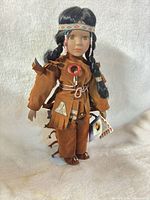 Full view of doll on stand showing outfit and accessories