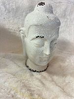 Front three-quarter view of white crackle-glazed Buddha head statue
