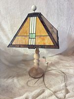 Full view of lamp showing stained glass shade, wooden base and cord