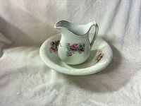 Porcelain pitcher resting inside matching basin