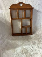 Front view of wooden wall shelf showing eight compartments and heart cutout crest