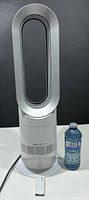 Full view of Dyson AM09 fan heater with remote and water bottle for scale