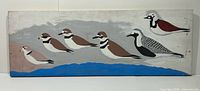 Full view of wooden plank painting showing six painted shorebirds over water