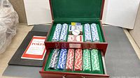 Open wooden case showing chips, decks, dealer button, dice, booklet