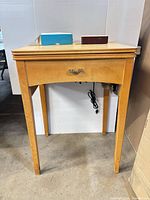 Overall view of light wood sewing cabinet with drawer