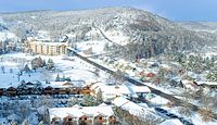 Aerial winter view of Holiday Valley resort buildings, slopes and surrounding snow-covered landscape