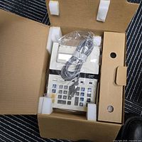 Calculator in original foam and plastic with cord visible