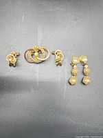 Overview of brooch and two earring pairs on dark background