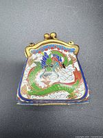 Front view of cloisonné purse pendant showing dragon design and brass frame