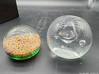Two paperweights side by side: clear orb and millefiori design