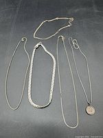 Group of five silver-tone necklaces laid out