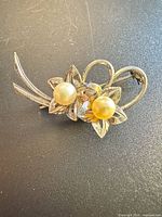 Front view of sterling silver floral brooch with two pearls