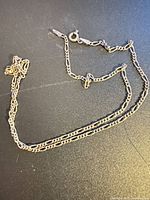 Entire sterling silver Figaro chain laid flat showing full length and clasp