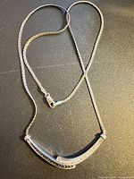 Full view of sterling silver necklace showing rope chain and curved bar pendant