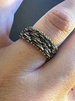 Ring on finger displaying woven link design and patina