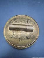 Closed compact top view showing engraved lid and lipstick holder