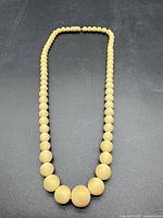 Full view of necklace laid flat showing graduated wooden beads