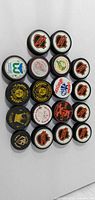 Front view showing 18 hockey pucks with assorted logos