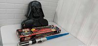 Boxed Darth Maul lightsaber, blue loose lightsaber, Vader case on table
