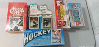 Overview of six hockey card items including O-Pee-Chee box, Team Canada ’72 box, two 1990 Singles blister packs and two small NHL Hockey boxes