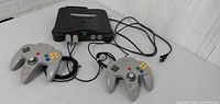 Front view of Nintendo 64 console with two grey controllers and power cord
