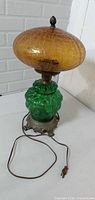 Full view of lamp showing green glass body, amber crackle shade, metal base, cord