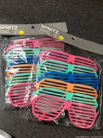 Front view of two sealed packs showing colorful shutter sunglasses