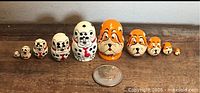 All twelve dog nesting dolls lined up beside quarter for scale