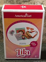 Front of sealed American Girl Lila Accessories box showing contents depiction and age rating 8+