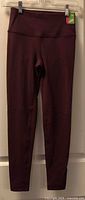 Full view of burgundy leggings hanging on hanger