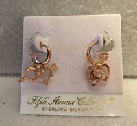 Front view of rose-gold tone heart and arrow earrings on branded card