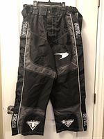 Front view of padded black and grey FORCE TEAM pants hanging