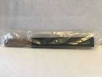 Entire strop in plastic wrap showing wooden handle and black leather side