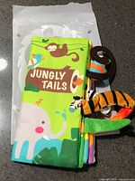 Front view of Jungly Tails cloth book in sealed package