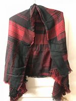 Full view of black and pink plaid blanket scarf hanging showing pattern and fringe