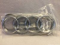 front view of both chrome Audi four-ring emblems in clear plastic